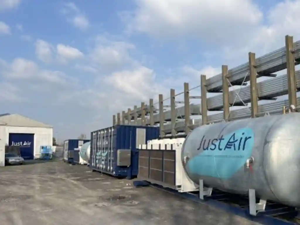 Buitenopstelling van JustAir persluchtinstallaties met containers, persluchtvat en leidingwerk voor industriële toepassingen.